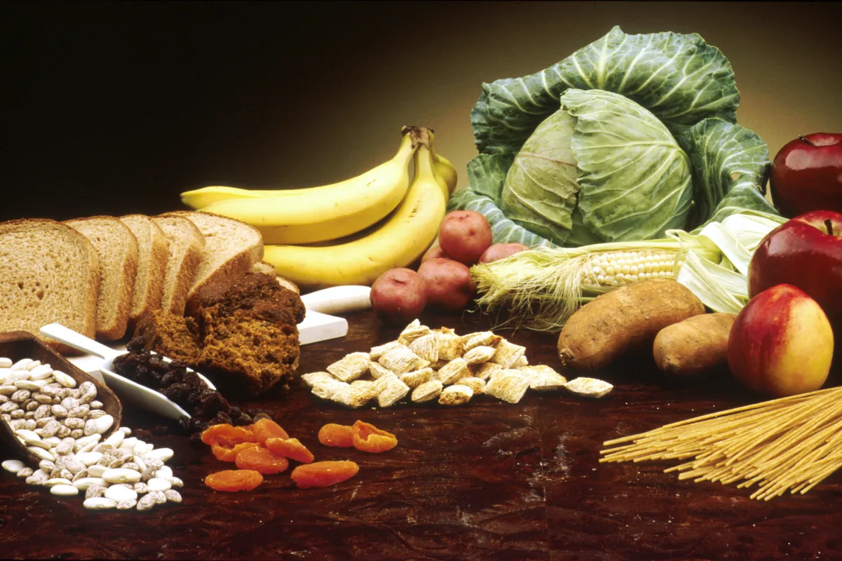 Fruit, vegetables, beans, bread and grains laid out on a wooden table